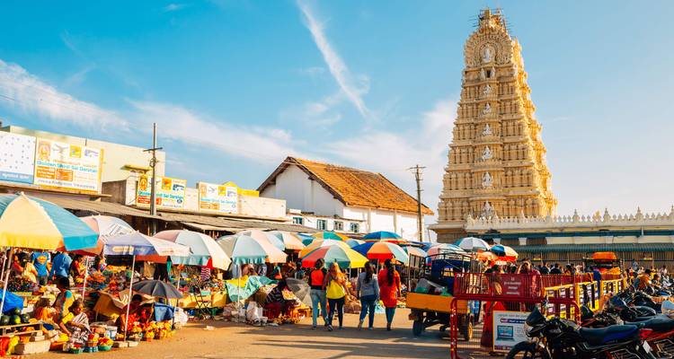 Kleurrijke lokale markt met tempel op de achtergrond.