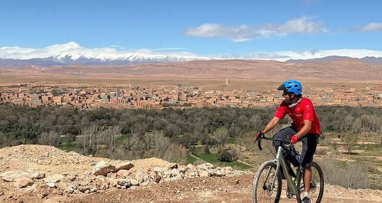Cycliste surplombant une ville désertique avec des montagnes.