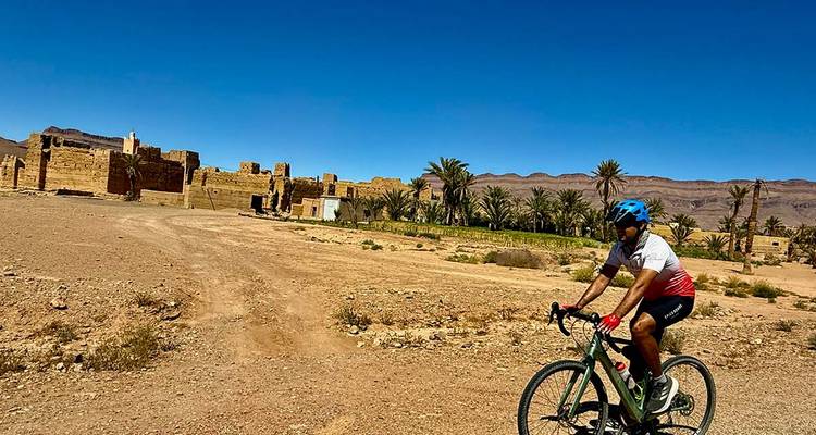 Cycliste traversant un paysage désertique avec des ruines.