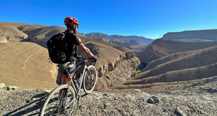 Cycliste surplombant un canyon dans un paysage désertique.