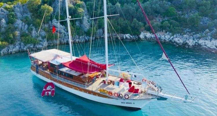 Zeilboot geankerd in een rustige baai omringd door rotsachtige kustlijn.