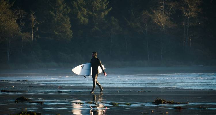 Surfeur marchant le long du rivage à une plage.