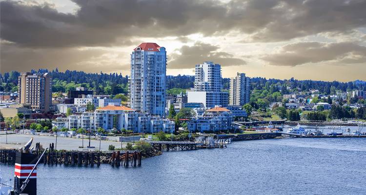 Vue sur la ville depuis le front de mer avec des bâtiments modernes sous un ciel nuageux.