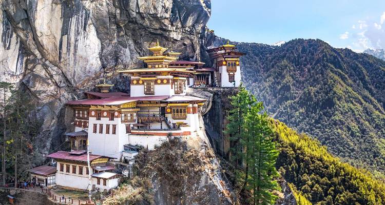 Famed cliff-hugging Tiger's Nest monastery perched high above a forested valley under clear skies.