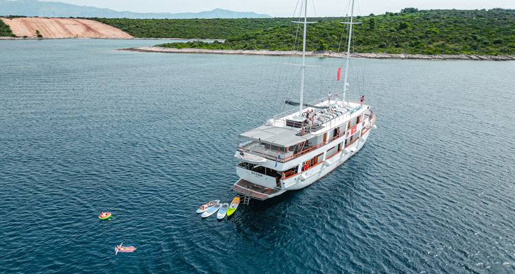 Yacht anchored in a bay with a hilly backdrop.