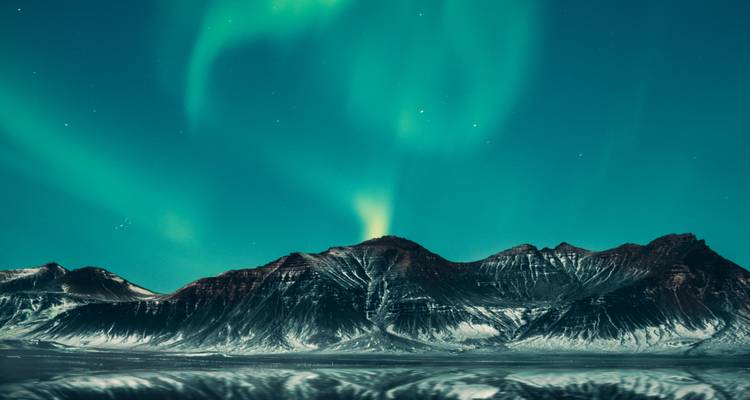 Northern lights over a mountain range at night.
