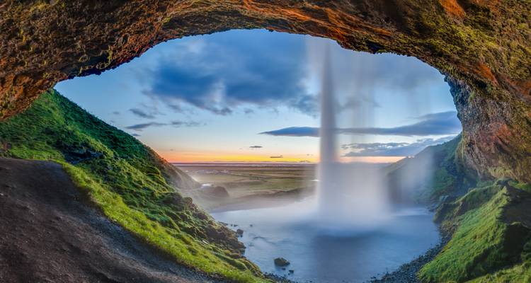 View from behind a waterfall during sunset.
