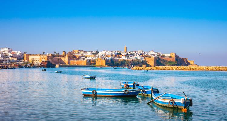 Coastal city with small boats on calm waters under a clear blue sky.