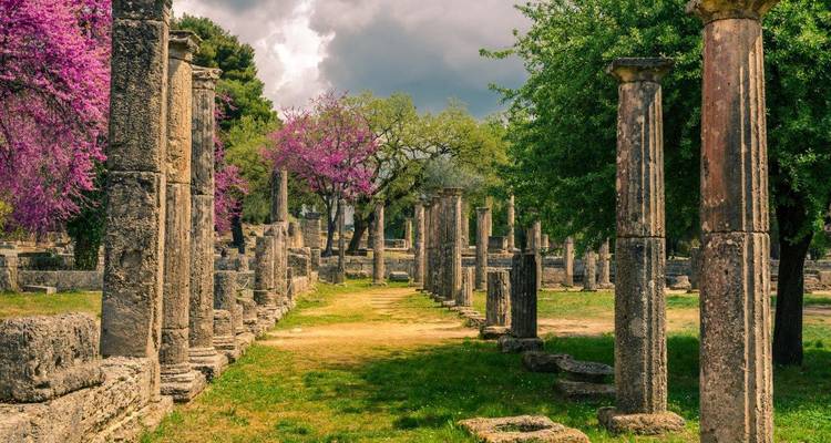 Ruines et colonnes parmi une végétation luxuriante et des fleurs.