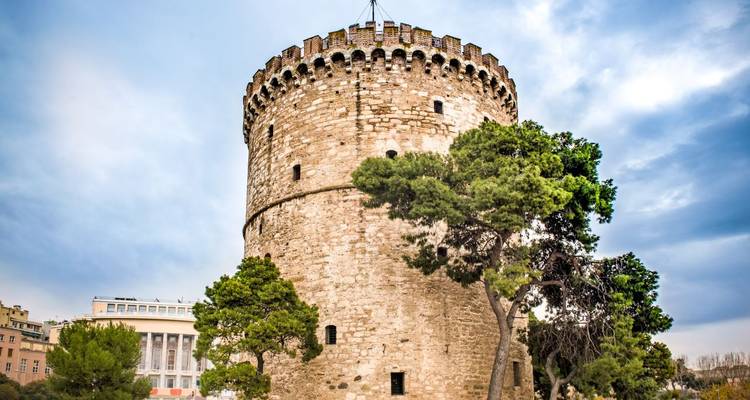 Tour historique entourée d'arbres et de bâtiments.
