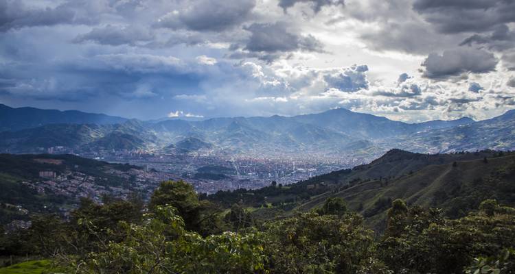 Panoramic view of a city surrounded by mountains and clouds.