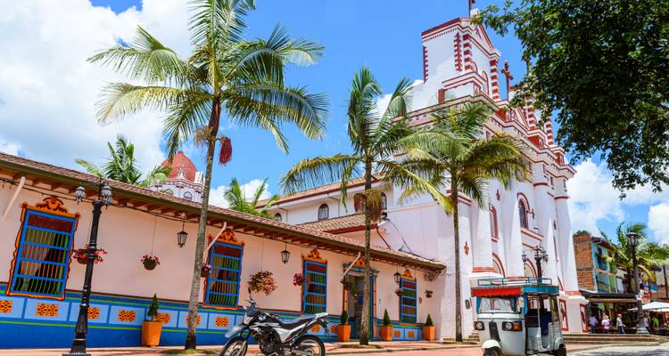 Colorful buildings and a church in a Colombian town square.