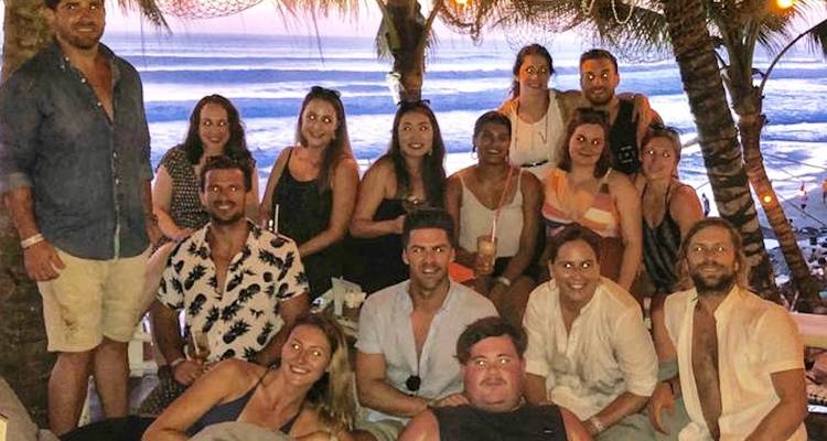 Foto de grupo en un bar junto a la playa después de la puesta de sol con olas del océano de fondo
