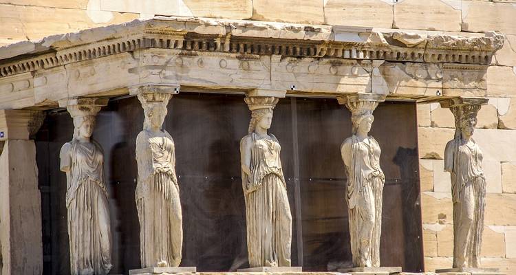 Estatuas de piedra de mujeres que sostienen un templo griego antiguo.