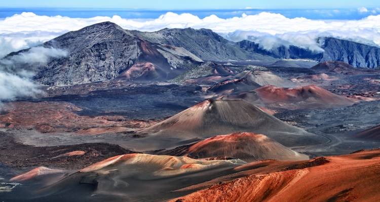 A volcanic landscape with red and black terrain and mountains.