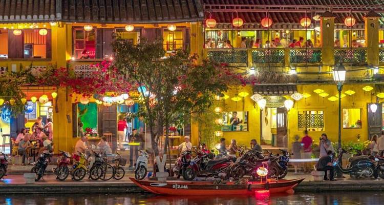 Bustling waterfront with yellow buildings and a boat.