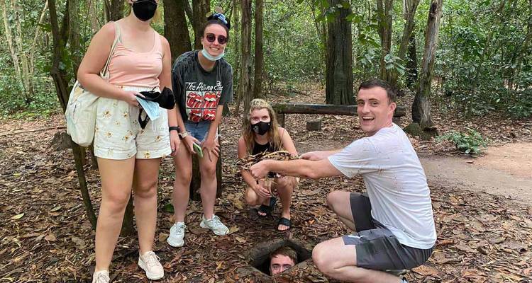 Group of tourists posing by a small opening in a forest.