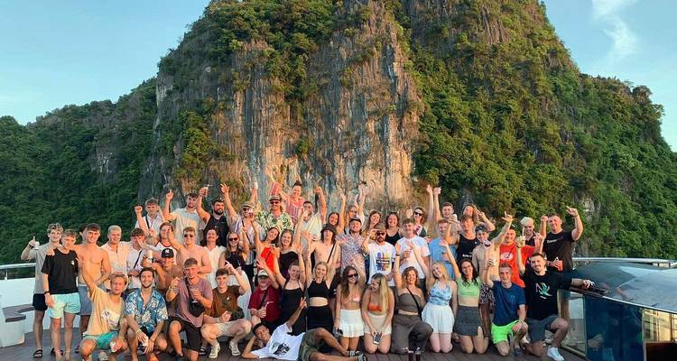 Large group of tourists posing together on a boat with a scenic background.