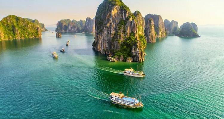 Vue majestueuse de bateaux naviguant dans des eaux turquoise au milieu de formations karstiques.
