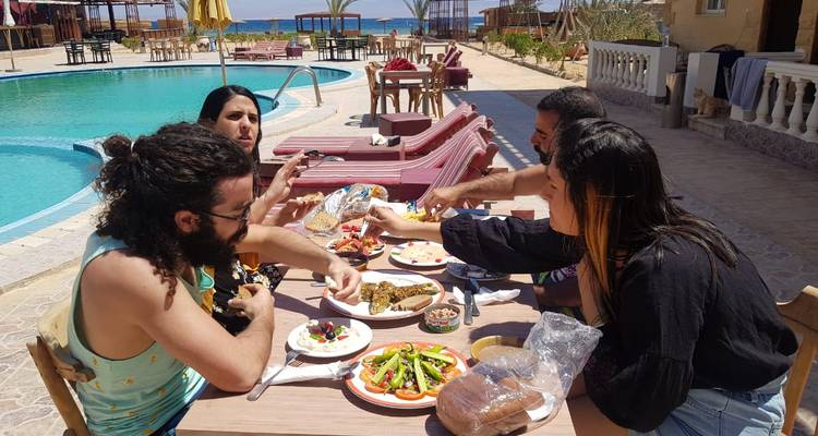 People enjoying a meal outdoors by a swimming pool.