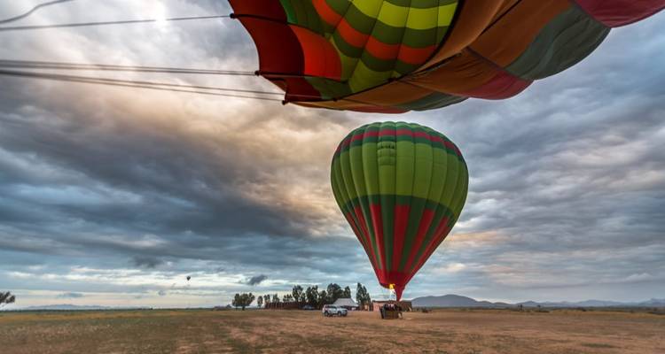 Montgolfières se préparant au vol au-dessus d'un paysage au lever du soleil.