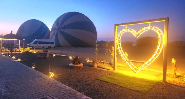 Montgolfières dégonflées avec un cadre en forme de cœur décoratif illuminé au premier plan.