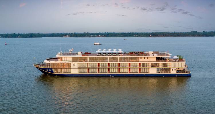 Cruiseschip op een rivier met een beboste oever in de verte.