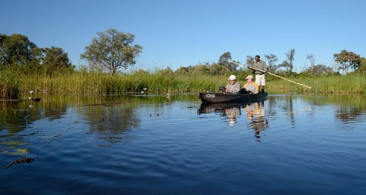 Canoa con personas en un delta tranquilo, rodeada de vegetación exuberante.