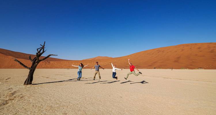 Grupo de personas saltando en un desierto con dunas de arena.