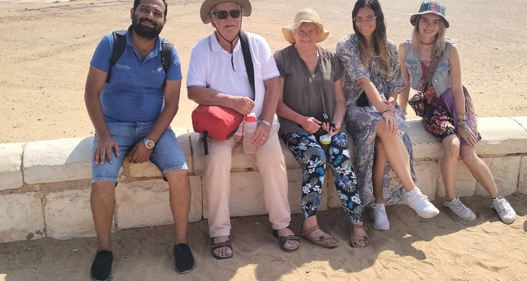 People sitting on a wall with desert scenery in the background.
