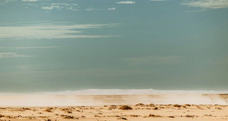 Desert landscape with sand dunes under a blue sky.