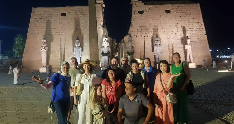 Group posing in front of ancient Egyptian ruins at night