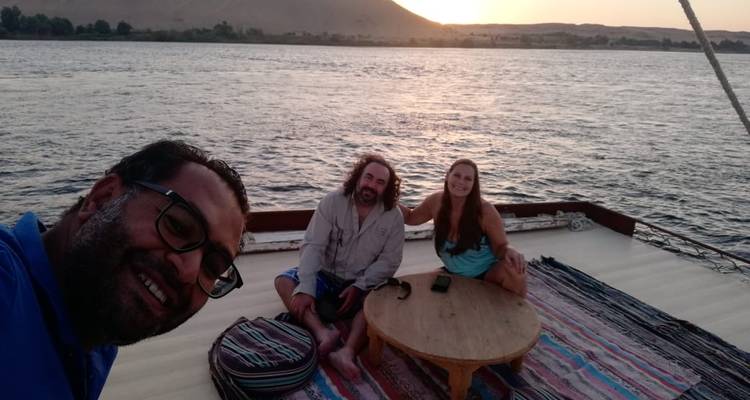 Three people on a boat enjoying the sunset on the river
