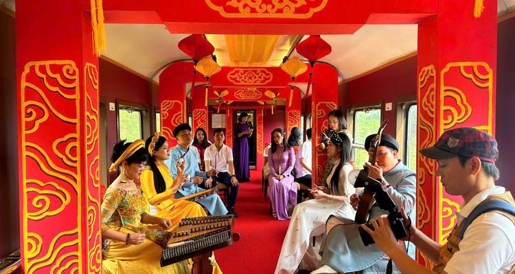 People in traditional attire inside a train with vibrant red interior.