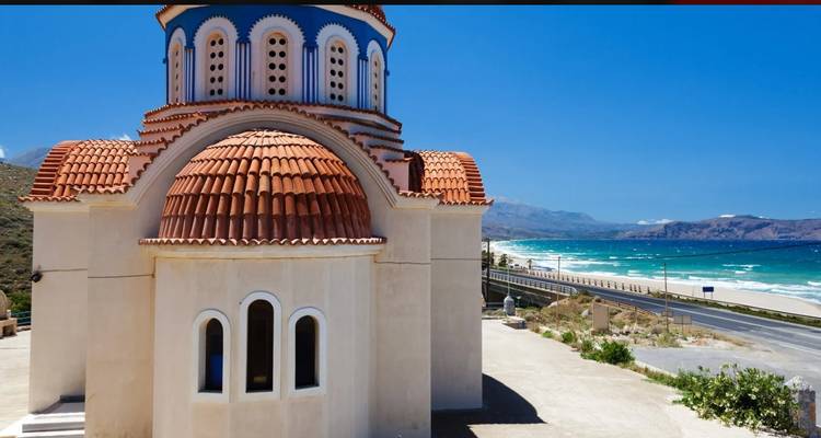 Église grecque traditionnelle avec dôme orange près de la côte.