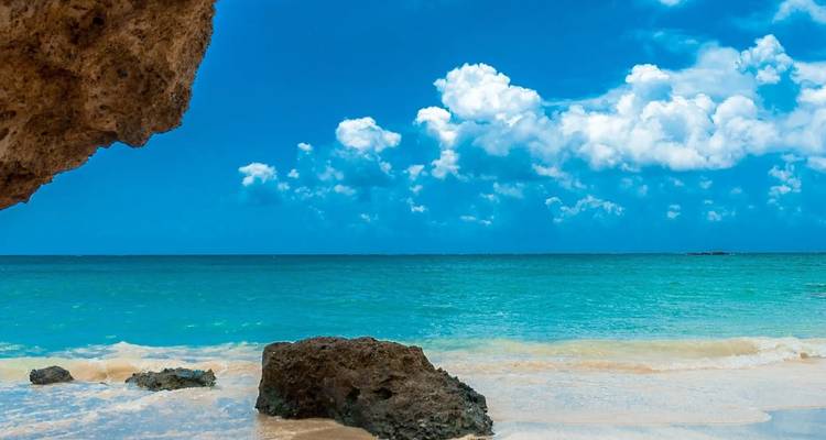 Mer et ciel bleu clair avec une plage rocheuse.