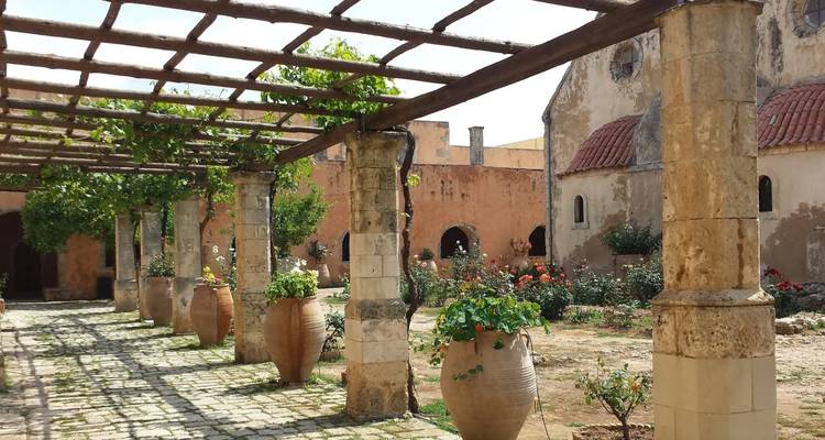 Ancienne cour de monastère avec colonnes de pierre et poterie.