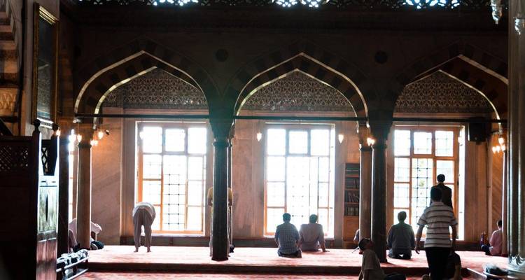 Interieur van een moskee met mensen die bidden.