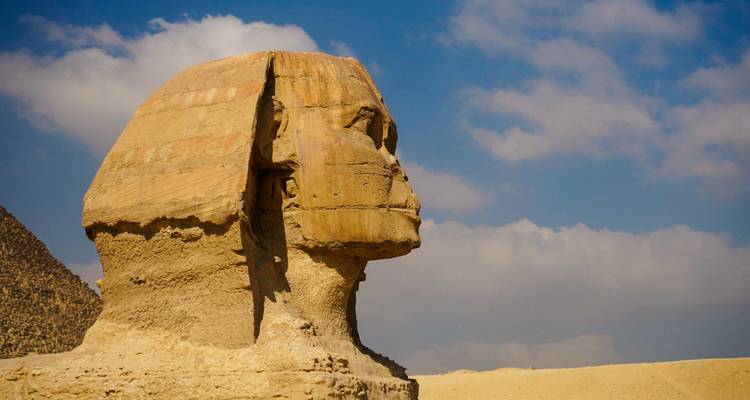 Zijprofiel van de Grote Sphinx van Giza tegen een gedeeltelijk bewolkte hemel.