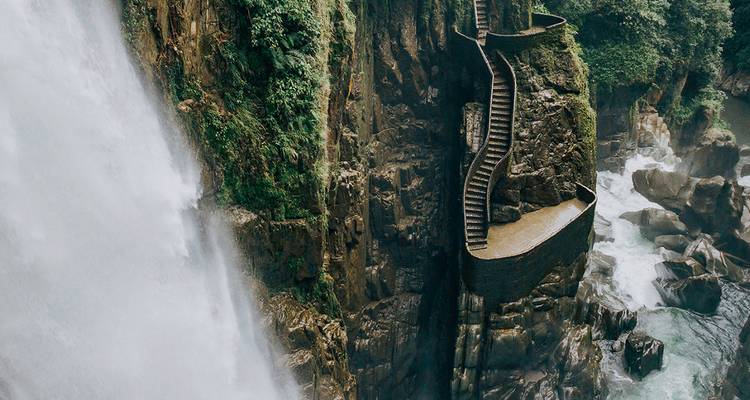 Poderosa cascada precipitándose junto a una dramática escalinata de piedra aferrada a la pared del acantilado.