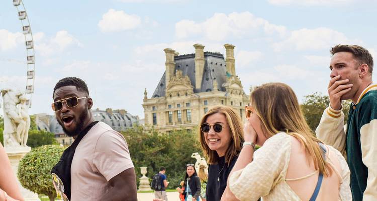 Group of friends laughing near the Louvre Museum with historic palace building behind them.