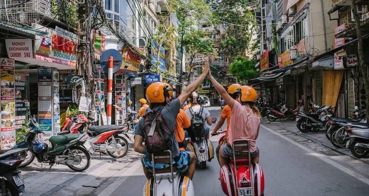 Gruppe von Menschen auf Rollern in einer belebten vietnamesischen Straße.