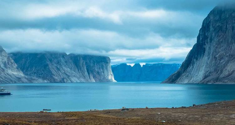 View of a fjord with cliffs and a cloudy sky.