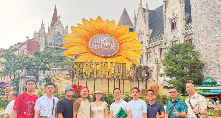 Groupe posant devant un panneau de festival avec un château en arrière-plan.