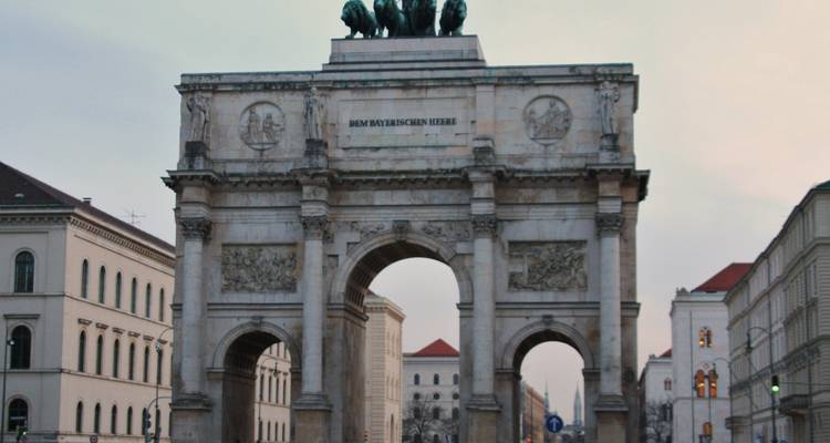 Arc de triomphe dans la ville avec un char tiré par des chevaux au sommet.