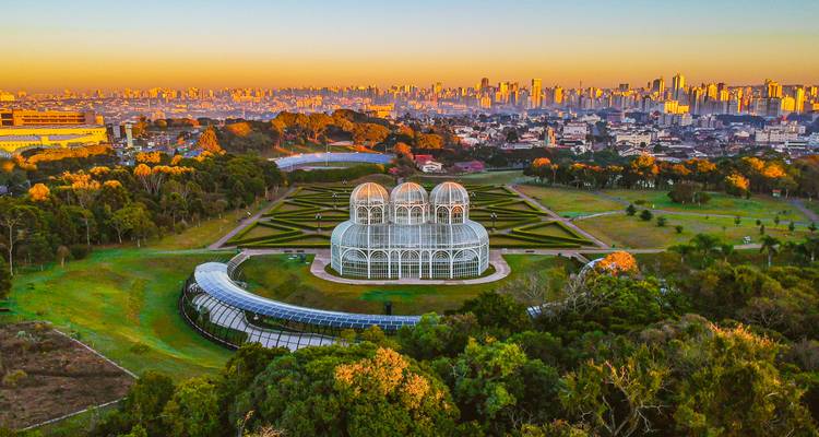 Luchtfoto van zonsopgang met Curitiba's iconische Botanische Tuin met glazen koepel en de skyline van de stad.