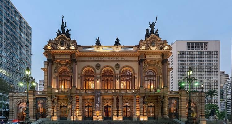 Verlichte gevel van het São Paulo Gemeentelijk Theater bij schemering, met prachtige architectonische details.
