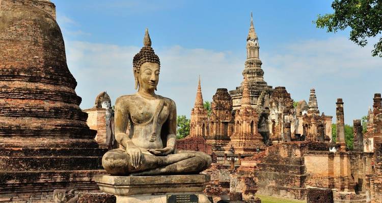 Statue de Bouddha assis dans un cadre de ruines de temple.