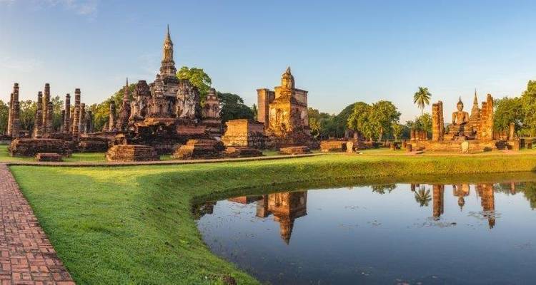 Boeddhabeelden en tempelruïnes bij een vijver.