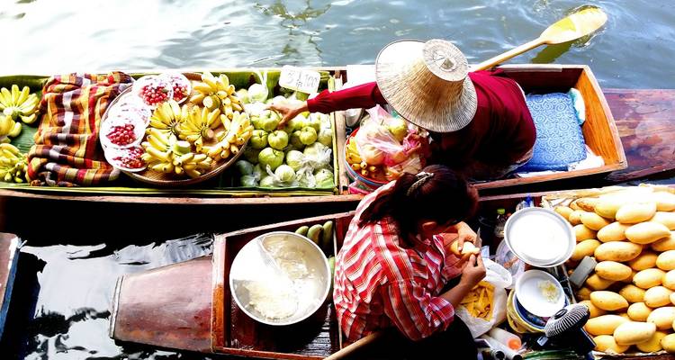 Des gens vendant des fruits sur des bateaux traditionnels dans un marché fluvial.